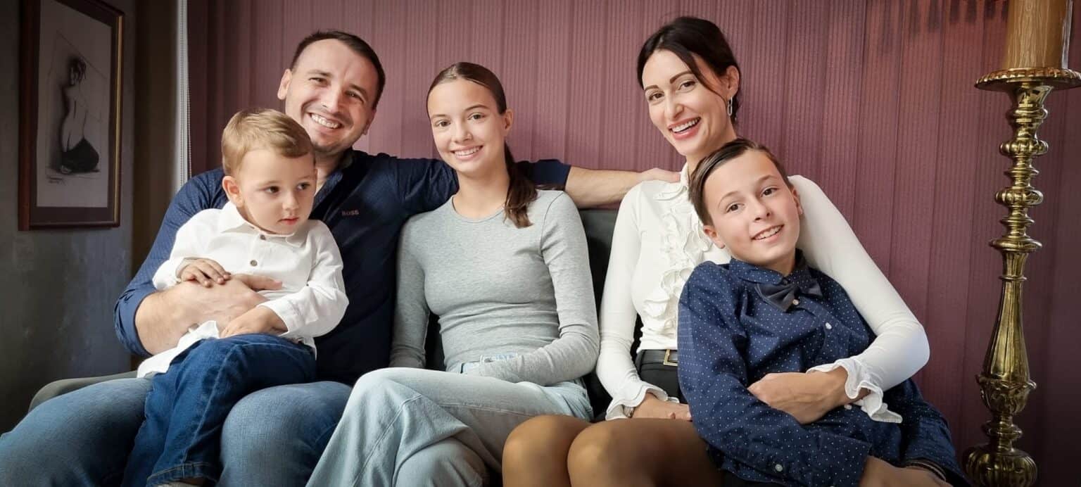 Familie zâmbitoare stând pe canapea împreună.